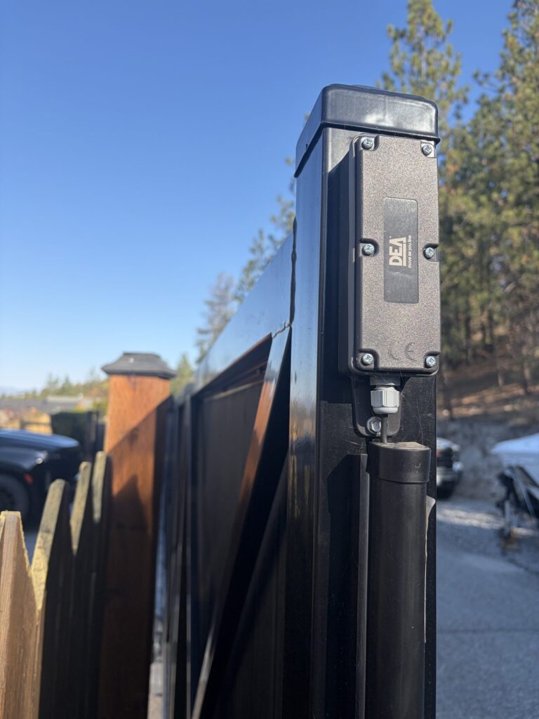 DEA wireless edge sensor transmitter mounted on the end post of a black cantilever gate